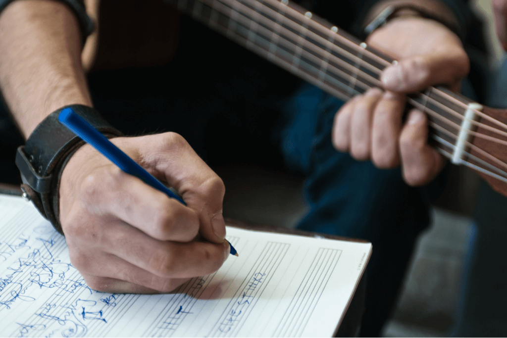 singer songwriter with guitar learning how to write a song, writing a song, playing a song